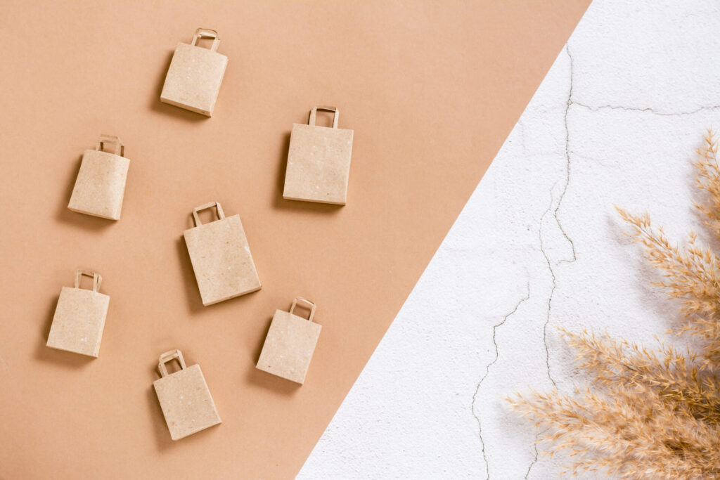 Craft paper shopping bags on a two-tone background. Sustainable lifestyle. Top view.