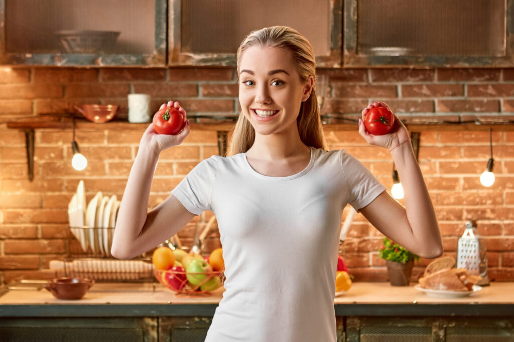 Veggies don t cause wedges. Happy young woman cutting fresh vegetables in modern kitchen. Cozy